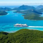 Freighter cruising in turquoise waters near lush islands.